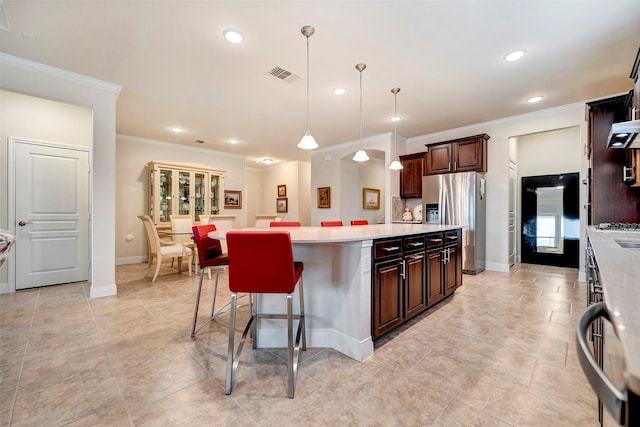 kitchen featuring stainless steel refrigerator with ice dispenser, dark brown cabinets, pendant lighting, a center island, and a breakfast bar area