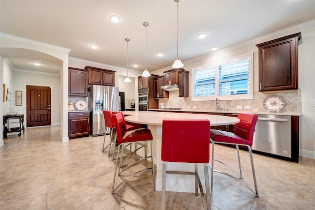 kitchen with stainless steel appliances, a kitchen breakfast bar, tasteful backsplash, pendant lighting, and a kitchen island