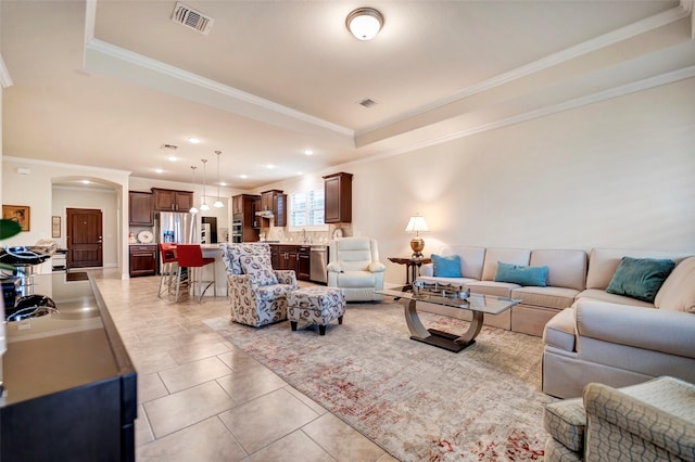 tiled living room featuring a raised ceiling and ornamental molding