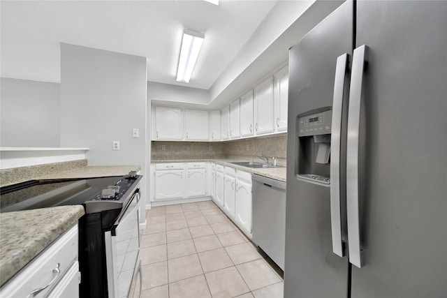 kitchen with decorative backsplash, appliances with stainless steel finishes, sink, light tile patterned floors, and white cabinetry