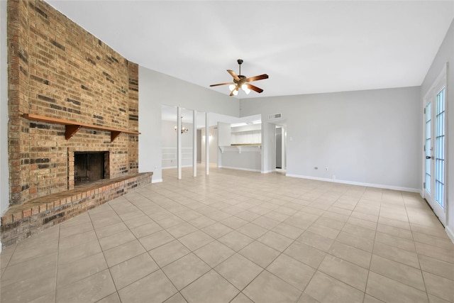 unfurnished living room featuring a wealth of natural light, light tile patterned flooring, ceiling fan with notable chandelier, and a brick fireplace