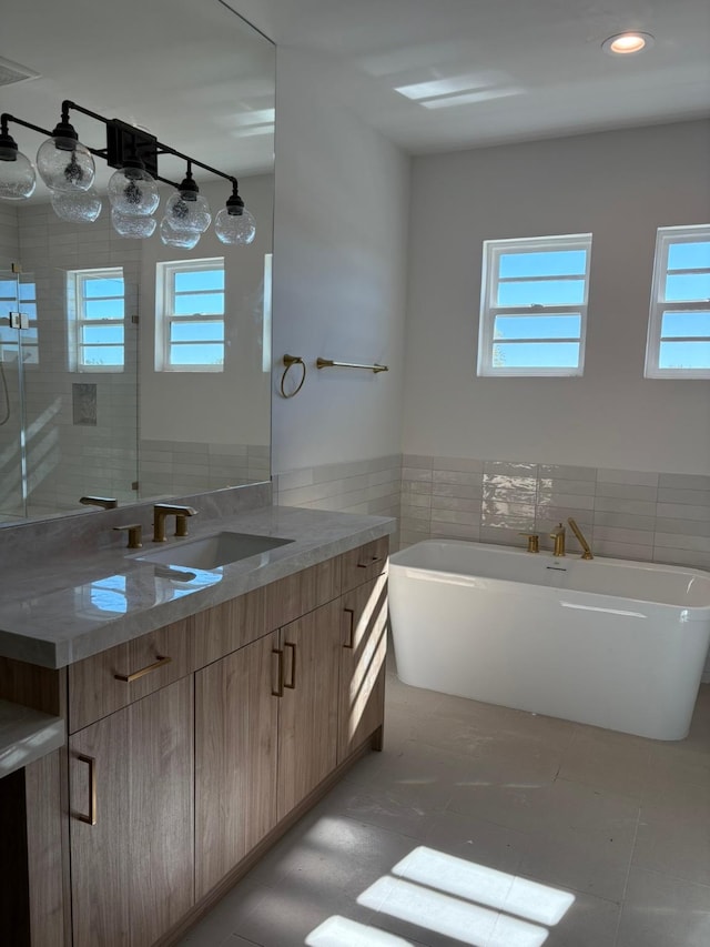 full bath featuring vanity, tile walls, a freestanding bath, wainscoting, and a stall shower