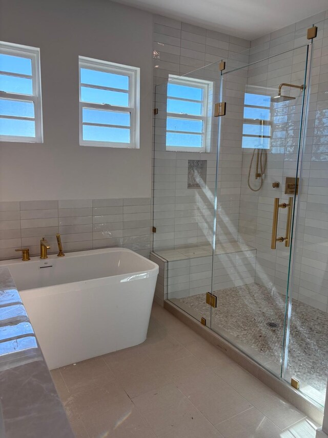 bathroom with tile patterned flooring, separate shower and tub, and tile walls