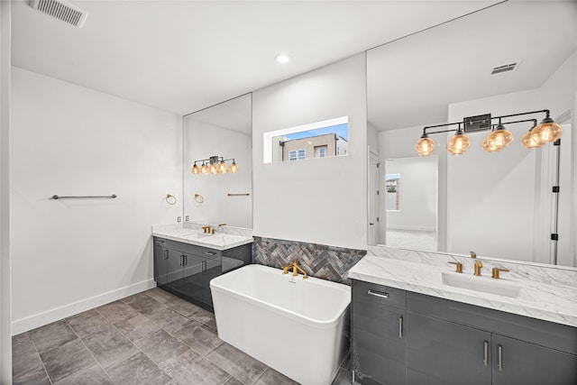 bathroom with a freestanding bath, visible vents, two vanities, and a sink