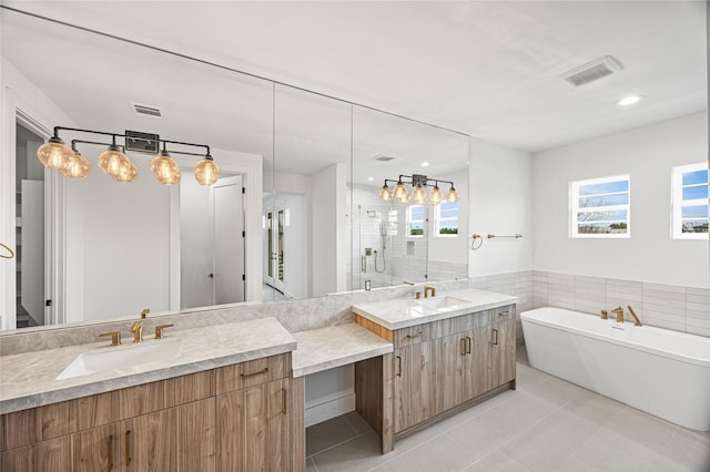 full bathroom featuring two vanities, a soaking tub, visible vents, and tile patterned floors