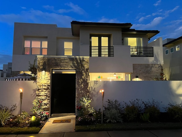 contemporary home with stone siding, fence, and stucco siding