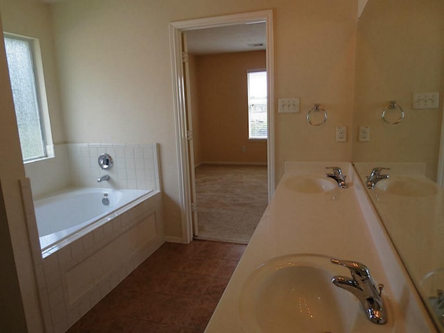 bathroom with tile patterned floors, tiled tub, and vanity