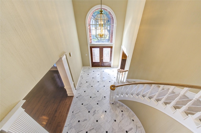 foyer entrance featuring french doors, a notable chandelier, and a high ceiling