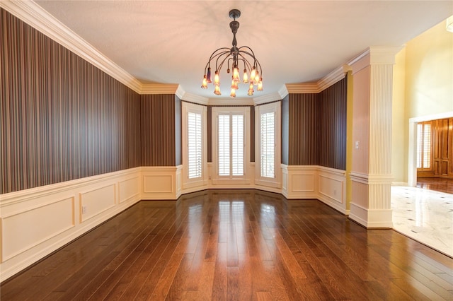 unfurnished room with dark hardwood / wood-style floors, ornate columns, crown molding, and a chandelier