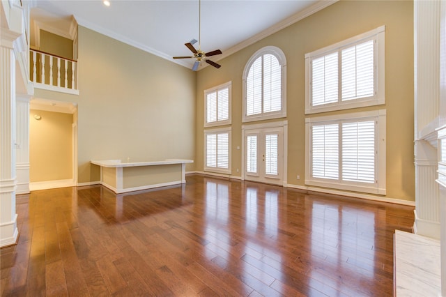 unfurnished living room with a high ceiling, dark hardwood / wood-style floors, ceiling fan, and ornamental molding