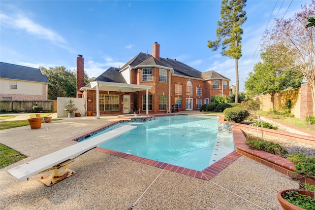 view of pool featuring ceiling fan, a diving board, a patio area, and an in ground hot tub