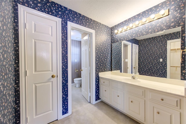 bathroom with vanity, toilet, and a textured ceiling