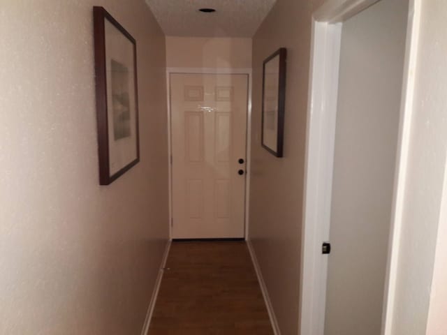 corridor featuring dark wood-type flooring and a textured ceiling