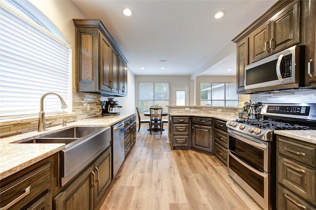 kitchen featuring sink, decorative backsplash, light hardwood / wood-style floors, dark brown cabinetry, and stainless steel appliances