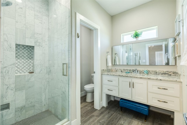 bathroom featuring vanity, hardwood / wood-style flooring, toilet, and a shower with shower door