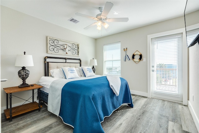 bedroom with multiple windows, ceiling fan, and hardwood / wood-style floors