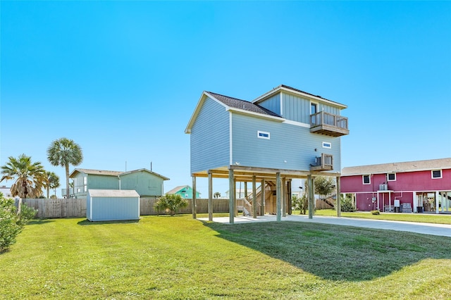 rear view of house with a carport, a storage unit, a balcony, and a lawn