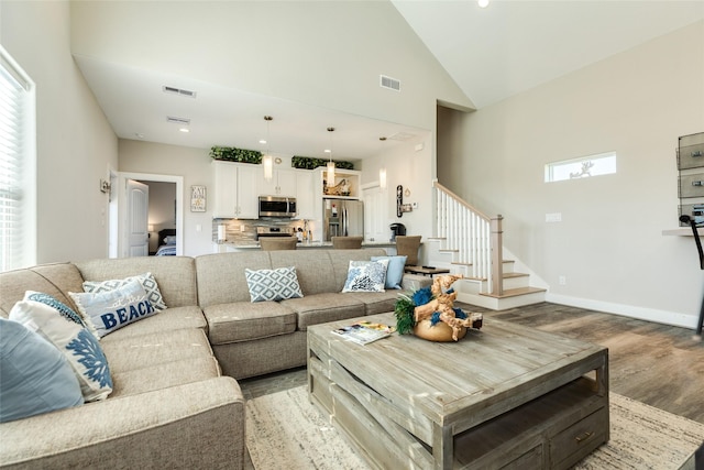 living room with light hardwood / wood-style floors, high vaulted ceiling, and a wealth of natural light