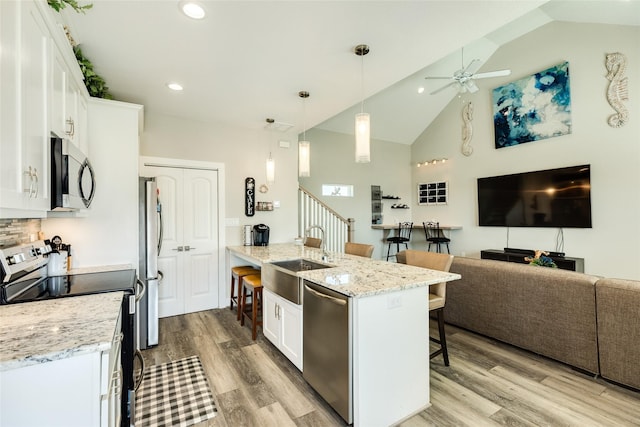 kitchen with a kitchen breakfast bar, decorative light fixtures, white cabinetry, and appliances with stainless steel finishes