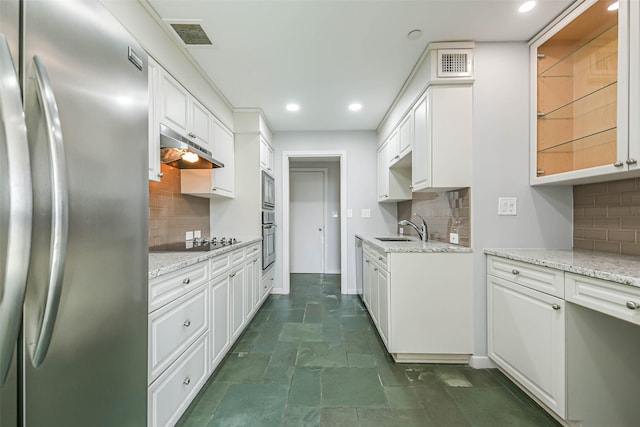 kitchen with white cabinetry, stainless steel appliances, light stone counters, and backsplash