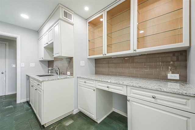 kitchen with tasteful backsplash, light stone countertops, sink, and white cabinets