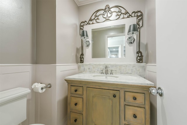 bathroom featuring tasteful backsplash, ornamental molding, vanity, and toilet