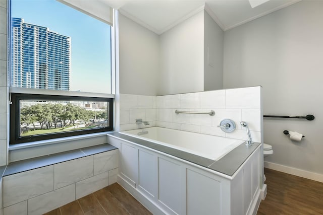 bathroom with hardwood / wood-style flooring, ornamental molding, toilet, and a bathing tub