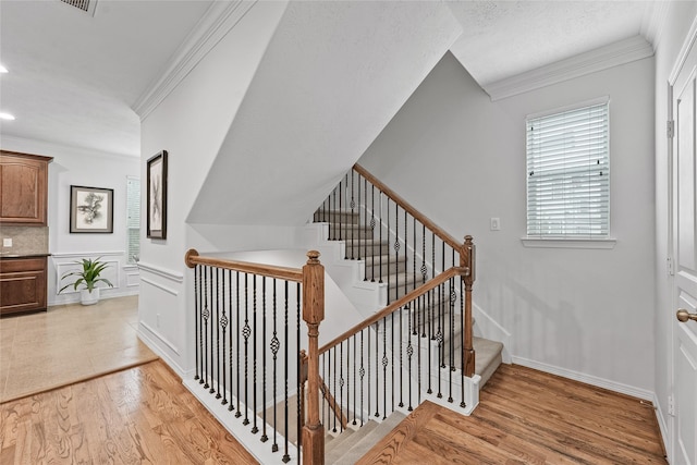 stairs with wood-type flooring and ornamental molding