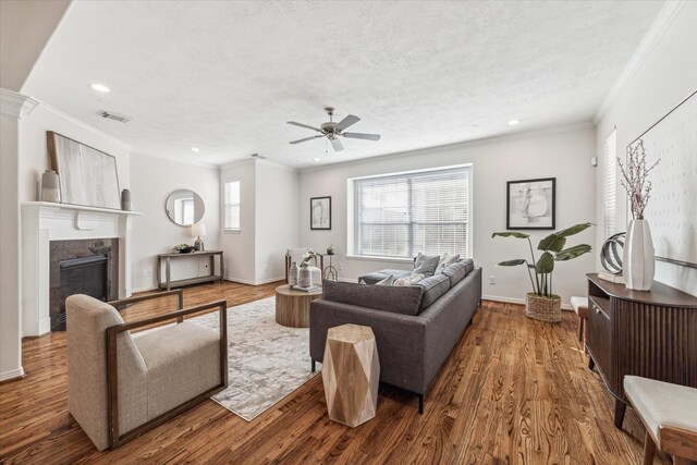 living room featuring a high end fireplace, a textured ceiling, hardwood / wood-style flooring, and ceiling fan