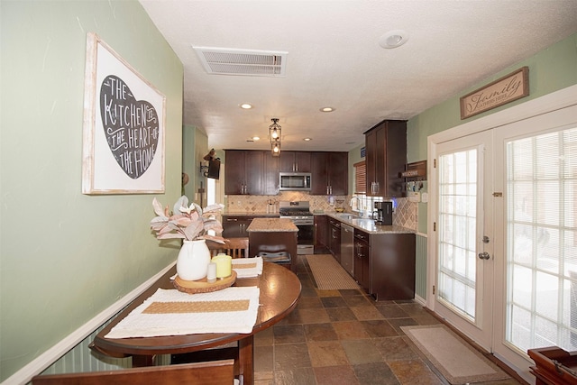 kitchen with a kitchen island, sink, backsplash, dark brown cabinetry, and stainless steel appliances