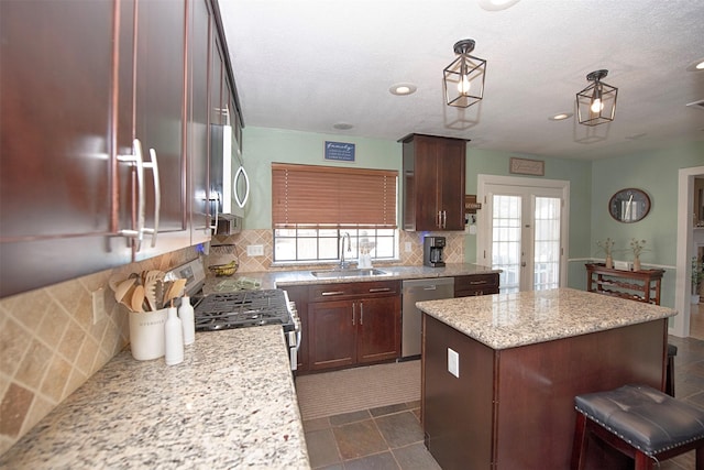 kitchen with sink, light stone counters, a center island, appliances with stainless steel finishes, and decorative backsplash