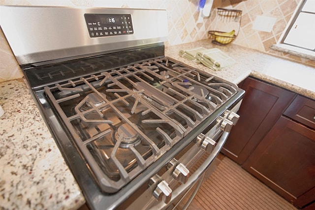 interior details with light stone counters, decorative backsplash, dark brown cabinetry, and gas stove