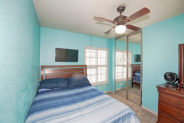 bedroom with ceiling fan, light colored carpet, and a closet