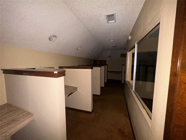 7555 Morley St, Houston, TX 77061 - corridor with vaulted ceiling, dark colored carpet, an upstairs landing, visible vents, and a textured ceiling