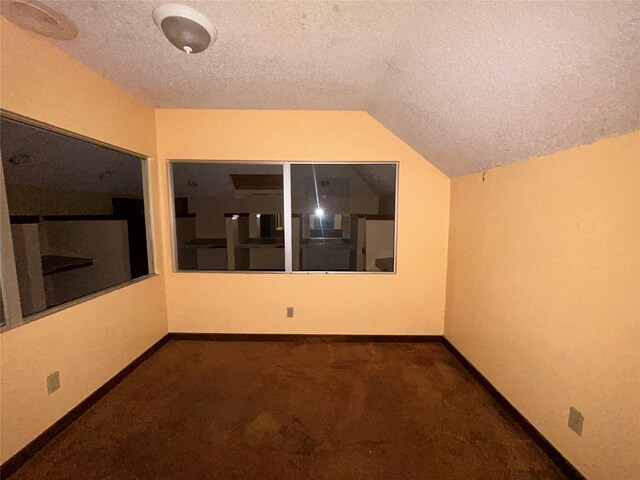 7555 Morley St, Houston, TX 77061 - empty room featuring a textured ceiling, lofted ceiling, carpet, and baseboards