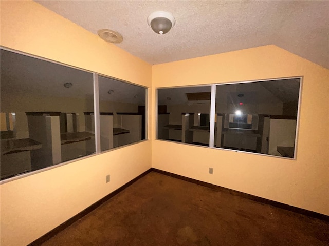 7555 Morley St, Houston, TX 77061 - empty room featuring dark carpet, a textured ceiling, vaulted ceiling, and baseboards