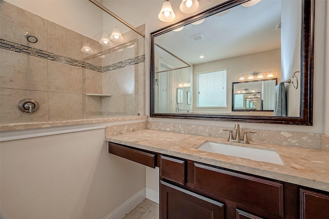 bathroom with tiled shower and vanity