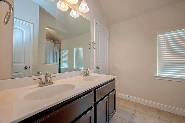 bathroom with tile patterned flooring, vanity, a healthy amount of sunlight, and vaulted ceiling