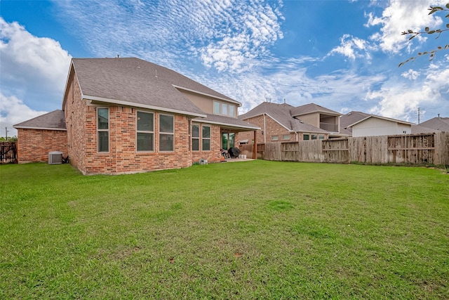 rear view of house with a yard and central AC