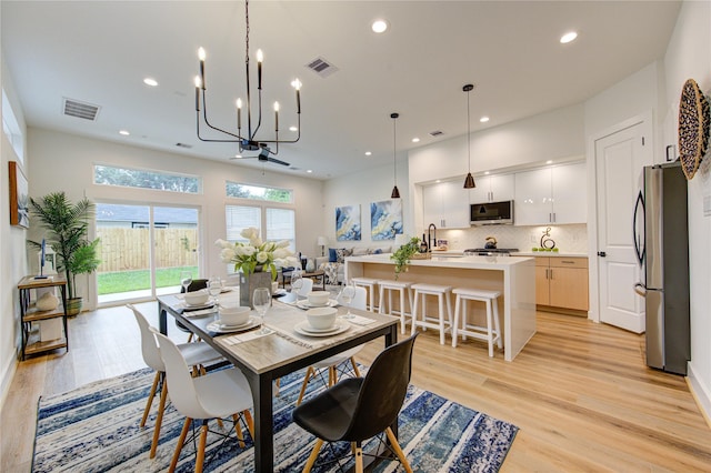 dining area featuring light hardwood / wood-style floors, sink, and a chandelier