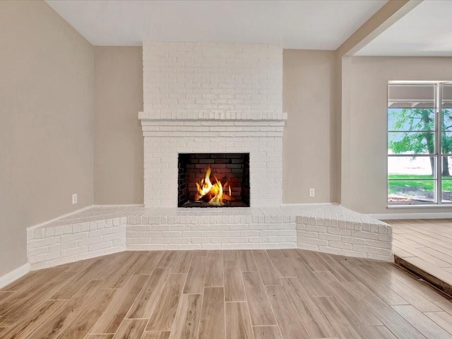 unfurnished living room featuring wood-type flooring and a brick fireplace