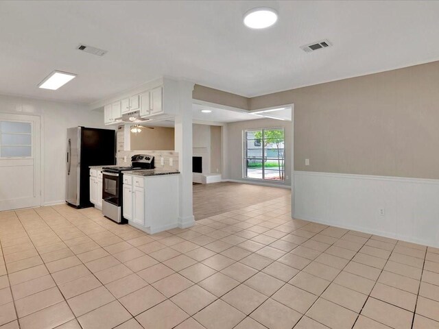 kitchen featuring appliances with stainless steel finishes, dark stone counters, ceiling fan, light tile patterned floors, and white cabinetry