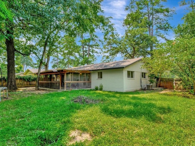 rear view of property with a trampoline, cooling unit, a lawn, and a sunroom