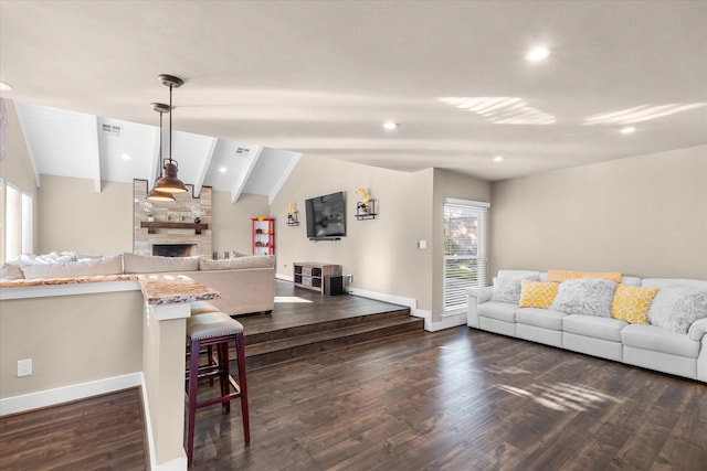 living room with vaulted ceiling with beams, a large fireplace, dark wood-type flooring, and plenty of natural light