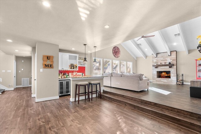 living room with lofted ceiling with beams, dark hardwood / wood-style floors, a fireplace, and ceiling fan