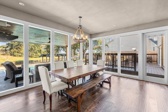 dining space with dark wood-type flooring, plenty of natural light, and a notable chandelier