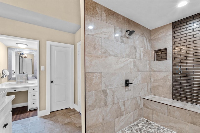 bathroom with a tile shower and vanity