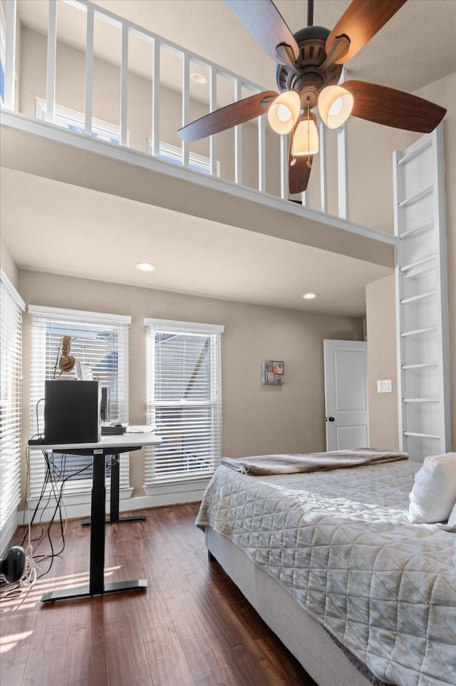 bedroom featuring ceiling fan, a towering ceiling, and dark wood-type flooring