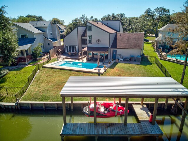 rear view of house with a patio area, a water view, and a fenced in pool