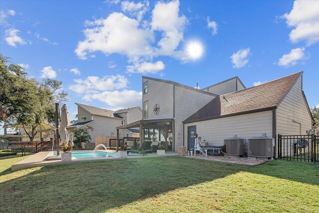 rear view of house with a yard, pool water feature, cooling unit, a fenced in pool, and a patio area